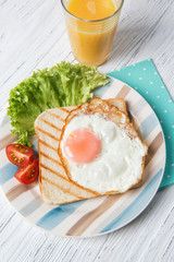 Simply healthy breakfast with fried egg on a toast bread and vegetables with orange juice