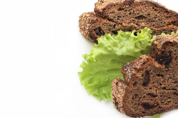 Pieces of homemade rye bread with cranberries and lettuce leaves on a white background for business card.