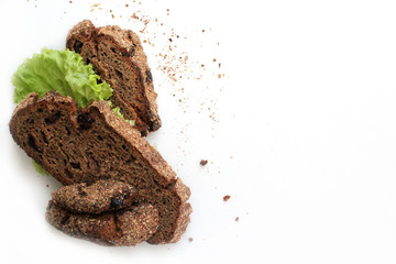 Pieces of homemade rye bread with cranberries and lettuce leaves on a white background with free space for text.