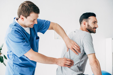 chiropractor massaging back of good-looking man in hospital - obrazy, fototapety, plakaty