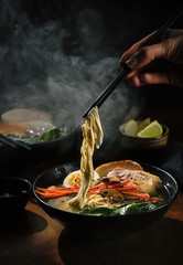 Hand with chopsticks takes noodles of ramen soup. Traditional Asian cuisine - 272702026