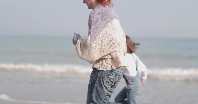 Mother And Child Running On The Beach In Autumn