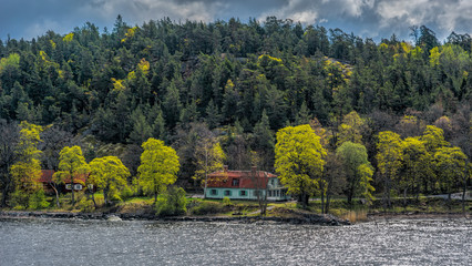 Stockholm archipelago in Baltic Sea. Picturesque summer houses on shore surrounded by coniferous forest at a spring day.
