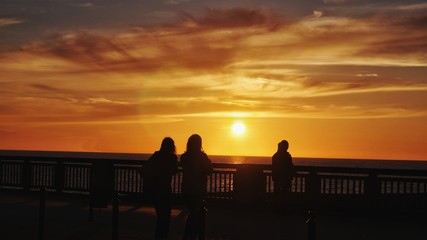 People on the boardwalk, watching the beautiful sunset on the sea