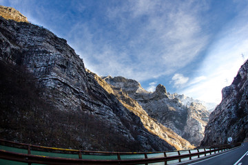 View from car window on snow-capped mountains and river. Winter road trip journey concept. Bosnia and Herzegovina. Empty road