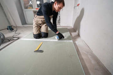Worker is using a polyurethane foam for gluing drywall at ninety degrees. Hand holding polyurethane expanding foam glue gun applicator