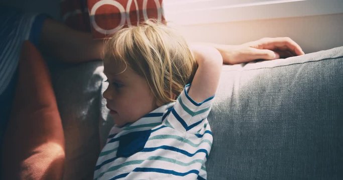 Toddler with his mother on sofa by the window