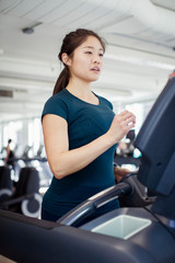 Fototapeta premium Confident female athlete running on treadmill in gym