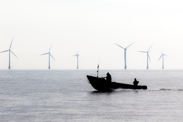 Controversial energy production. Wind farm turbines security. Patrol boat during green power...