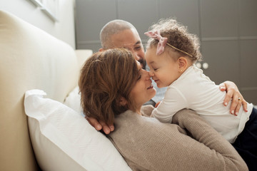 Obraz premium Side view of mother and daughter rubbing noses while relaxing on bed at home