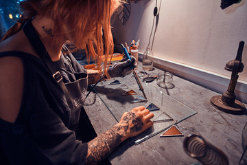 Young attractive designer is working at cozy handmade lamp studio.