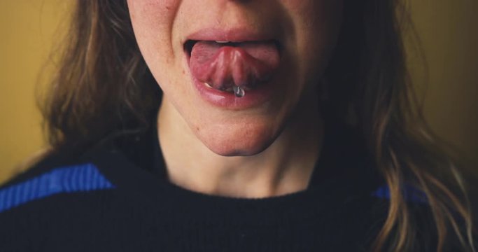 Young woman sticking out her pierced tongue