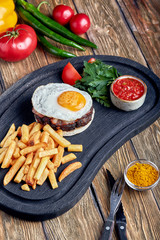 Beef steak with egg and salad from greens and vegetables. Wooden background, table setting, fine dining