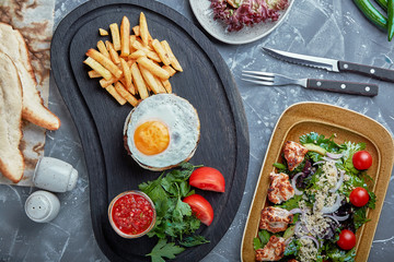Beef steak with egg and salad from greens and vegetables. Wooden background, table setting, fine dining