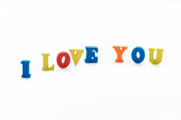 A Declaration of love consists of colored wooden letters standing on a white background. Love, isolate