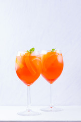 Aperol Spritz cocktail with mint leaves on a white background. A glass of summer alcohol cocktail with orange slices. Classic Italian drink coral color