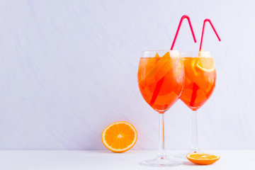 Aperol Spritz cocktail with mint leaves on a white background. A glass of summer alcohol cocktail with orange slices. Classic Italian drink coral color
