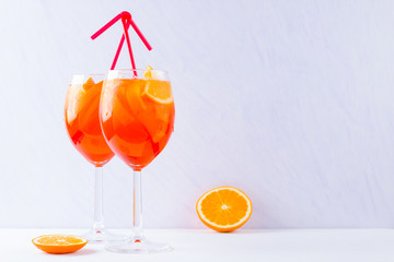 Aperol Spritz cocktail with mint leaves on a white background. A glass of summer alcohol cocktail with orange slices. Classic Italian drink coral color
