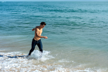 Young handsome muscular man on seashore in a sunny day