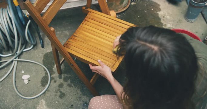 Young woman washing a chair in her yard