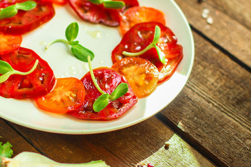 tomatoes salad with sunflower seedlings microgreen (carpaccio, sliced ​​raw vegetables). food background. top view. copy space