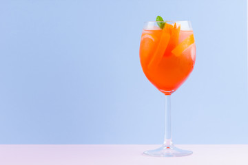 Cocktail Aperol Spritz on a blue pink background. Italian cocktail aperol spritz in pop art style. Summer trendy drink on pastel background