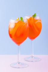 Cocktail Aperol Spritz on a blue pink background. Italian cocktail aperol spritz in pop art style. Summer trendy drink on pastel background