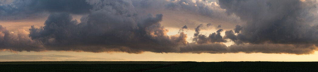 Leaden, storm clouds covered the sunset. Cumuliform cloudscape on blue sky. The terrain in southern Europe. Fantastic skies on the planet earth. Tragic gloomy sky. Panorama.