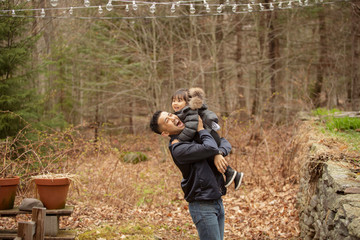 Fototapeta premium Side view of cheerful father carrying daughter while standing against bare trees in forest
