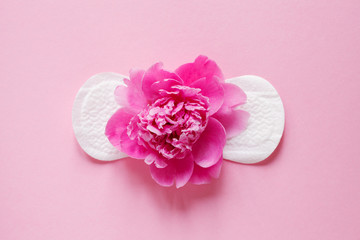 women intimate hygiene product, sanitary pad and beautiful fresh peony flower on pink background, flat layout