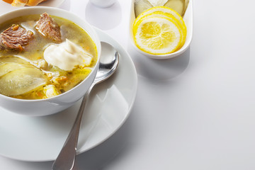 Soup Rassolnik with pickled cucumber and sour cream on a white background. Russian cuisine. Close up. Selective focus. For the menu.