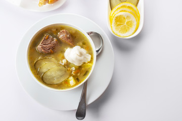 Soup Rassolnik with pickled cucumber and sour cream on a white background. Russian cuisine. Close up. Selective focus. For the menu.
