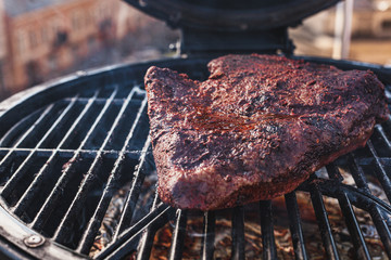 Close up on the blackened and charred bark of a smoked beef brisket, in a slow cooking background