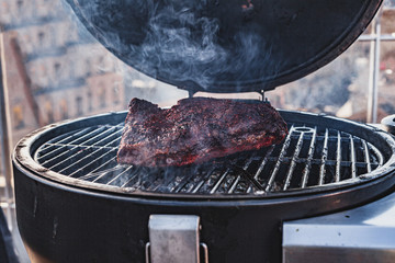 Close up on the blackened and charred bark of a smoked beef brisket, in a slow cooking background