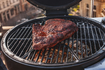 Close up on the blackened and charred bark of a smoked beef brisket, in a slow cooking background