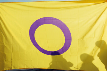 Yellow flag with purple o on it and human silhouettes on a gay parade Pride Selective focus