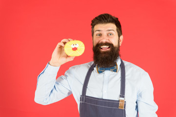 Glazed donut. Bearded well groomed man in apron selling donuts. Donut food. Baked goods. Sweets and cakes. Junk food. Hipster bearded baker hold donuts. Eat donut. Cheerful mood. Doughnut calories