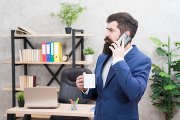 Man bearded businessman hold cup and smartphone. Mobile call. Start day with coffee. Coffee...