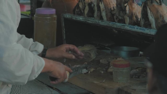 Close up of a man in a local Moroccan market stall roughly chopping up a fish preparing to make a traditional dish on the street from his cart