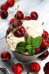 Cherry and vanilla ice cream scoop with fresh cherries and mint on a rustic background