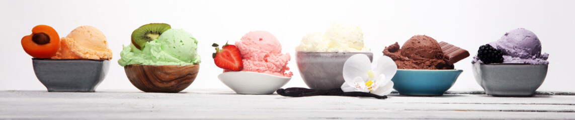 ice cream scoops of different colors and flavours with berries, nuts and fruits decoration on white background