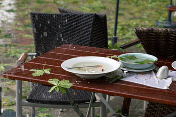 forgotten dishes on a table in the beer garden during a rain shower