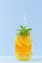 Infused water with fruits on blue background. Mug delicious refreshing drink of mix fruits with mint on blue background. Iced summer drink in mason jar. Minimalism