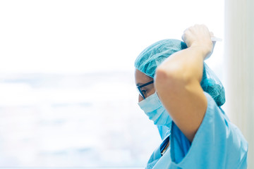 Female doctor tying surgical mask, preparing for surgery