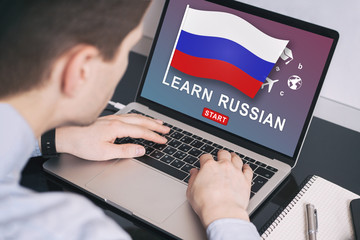Man working on laptop with LEARN RUSSIAN on a screen. Education learning russian language school concept.