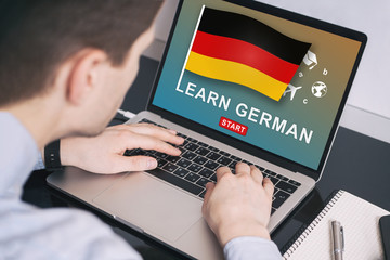 Man working on laptop with LEARN GERMAN on a screen. Education learning german language school concept.