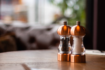 A bronze Salt and pepper shaker and grinder sit on a table inside a Irish restaurant
