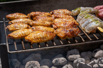 Mixed assortment of marinated meat, chicken, and prawns grilling on hot coals on a BBQ
