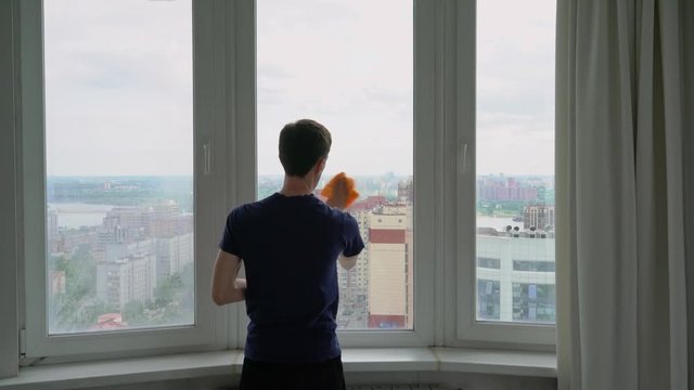 A Man Washes A Window Overlooking The City