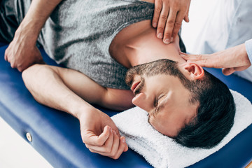 Fototapeta na wymiar chiropractor massaging neck of man lying on Massage Table